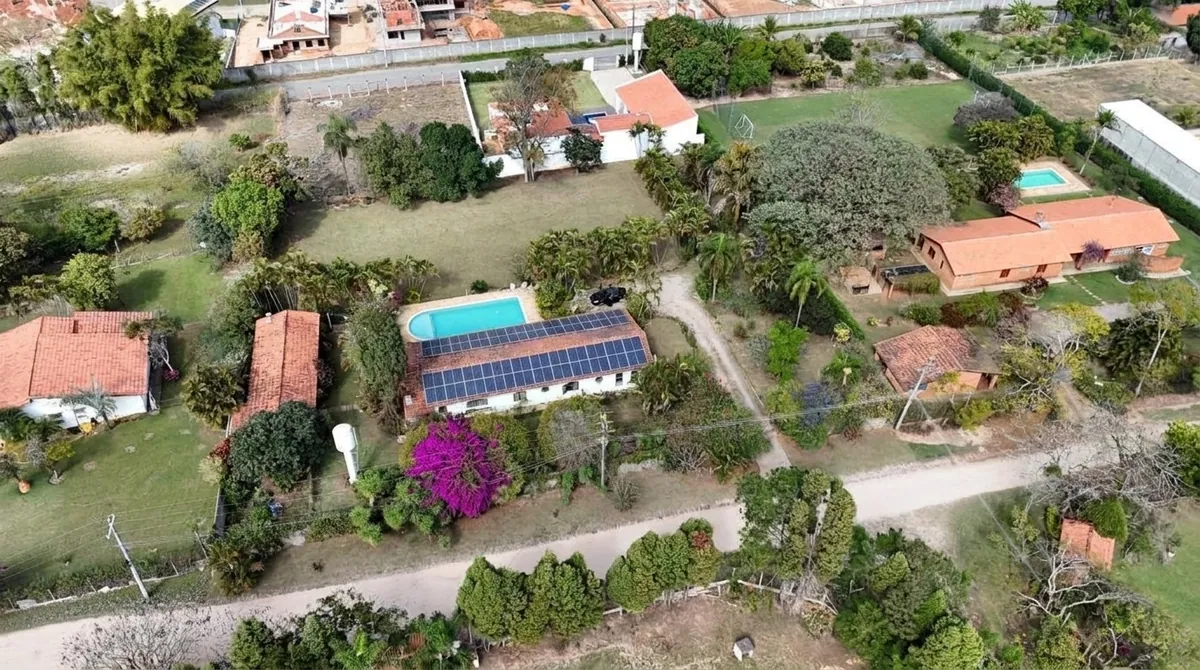 Vista aérea de chácara com sistema de energia solar no telhado cerâmico, ao lado da piscina